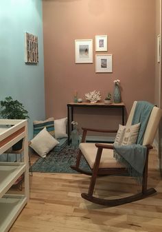 a living room with a rocking chair, rug and pictures on the wall