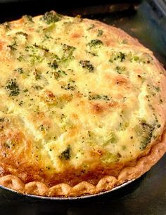 a quiche with cheese and broccoli on it sitting in an open oven