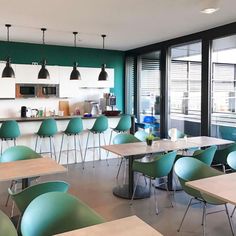 an empty classroom with green chairs and desks