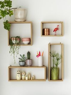 three wooden shelves with plants and pots on them in front of a wall mounted planter