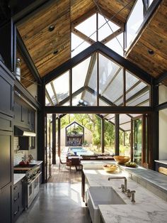 an open kitchen and dining area with large windows on the ceiling, along with stainless steel appliances