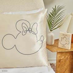 a pillow with a cartoon character drawn on it next to a lamp and a plant