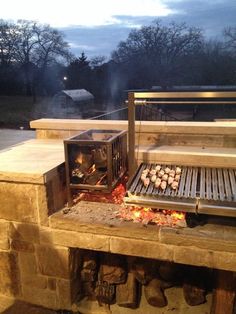 an outdoor grill with food cooking on it's sides and lights shining in the background