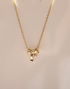 Inspired by ribbon-tied bows, this dainty and feminine necklace has a graceful design making it an ideal accessory for both casual and special occasions. Match it with the Bow Earrings for the full look. Find the matching bow earrings here. Length: 16" + 2" chain extender Bow Size: 12mm wide ✶This item is crafted with high quality 14K Gold Vermeil over. 925 Sterling Silver. For more information on these materials and how to care for your items, click here. Gold K Necklace, Gold Bow Necklace, Necklace Aesthetic Gold, Christian 2024, Sarah Logan, Silver Braided Ring, Ring Charm Necklace, Feminine Necklace