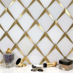 the wall is decorated with gold and white geometric tiles, including two perfume bottles and three other items