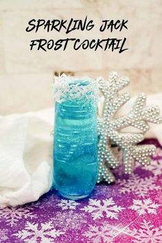 sparkling jack frost cocktail in a blue glass next to a snowflake ornament