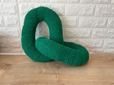 two green pillows sitting on top of a wooden table next to a white brick wall