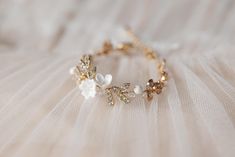 a close up of a bracelet with flowers on it's side and pearls in the middle