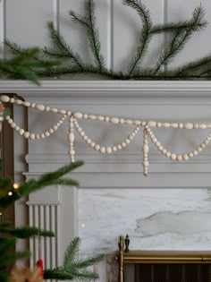 a fireplace decorated for christmas with white balls and garland hanging from the mantel above it