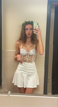 a woman taking a selfie in a bathroom mirror wearing a white skirt and corset