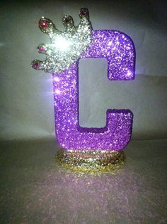 the letter c is made out of glitter and has a crown on top