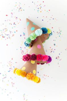 a party hat with pom poms on it and confetti around it