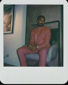 a man in a pink suit sitting on a chair