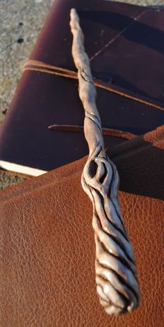 a close up of a metal object on top of a brown leather book cover with an intricate design