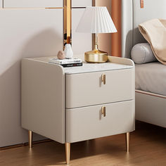 a nightstand with a lamp on it next to a bed