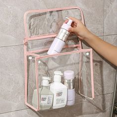 a person is holding an empty container in front of a wall mounted toiletries holder