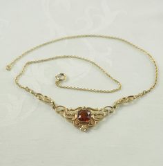 A charming Art Deco gold filled festoon necklace in yellow gold tone. Set to the center with an octagonal cut synthetic citrine tone spinel, 9mm in square, with a mille grain setting. In an ornate patterned mount with plain and patterned entwined scrolls, with a further scroll to each side. On a very fine link chain with a spring ring clasp,  Unmarked. Germany 1930-40. 5.1g   The decorative portion 9cm x 1.8cm.  In inches 3 1/2" x 5/8". 44cm long.  In inches  17 1/4". IN VERY GOOD VINTAGE CONDIT Vintage Necklace With Historical Design For Gift, Vintage Yellow Gold Jewelry With Historical Design, Vintage Pendant Necklace With Historical Design, Antique Yellow Gold Necklace With Historical Design, Vintage 14k Gold Necklace For Formal Occasions, Vintage Hallmarked Wedding Necklaces, Ornate 14k Gold Wedding Necklace, Ornate 14k Gold Necklace For Wedding, Vintage Gold Jewelry With Bail