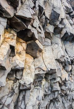 some rocks are stacked up on the side of a mountain wall with yellow and brown colors