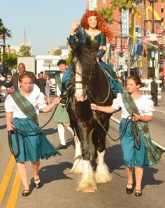 two women are leading a horse down the street