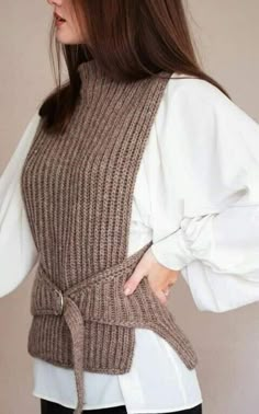 a woman in black pants and a white shirt is wearing a brown sweater with sleeves