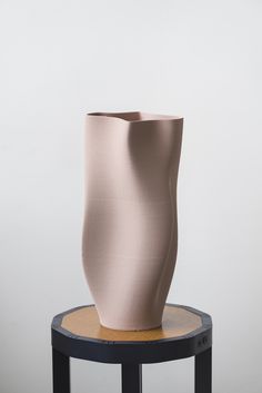 a large pink vase sitting on top of a wooden table next to a white wall