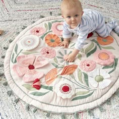 a baby is playing on a rug with flowers in the middle and leaves around it