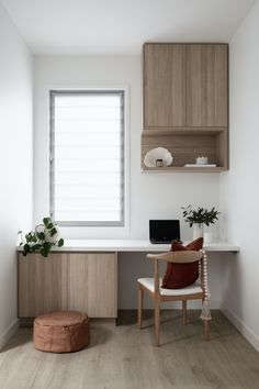 a white desk and chair in a small room with wooden shelves on the wall above it