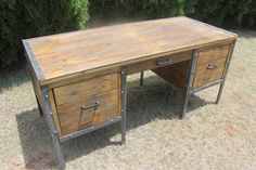 a desk made out of wood and metal with two drawers on each side, sitting in the grass