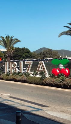 there is a sign that says ibiza with two cherries on it and palm trees in the background