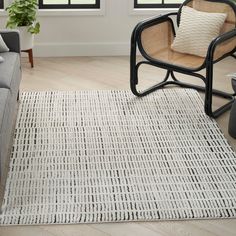 a living room with a gray couch and chair next to a white rug on the floor