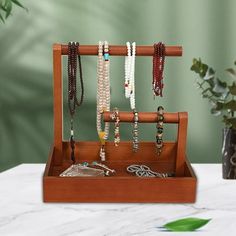 a wooden jewelry holder with bracelets and necklaces hanging from it's sides