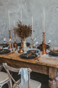 a wooden table topped with plates and candles