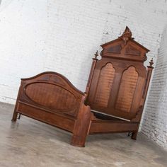 an antique wooden bed frame with intricate carvings on the headboard and foot board, against a white brick wall