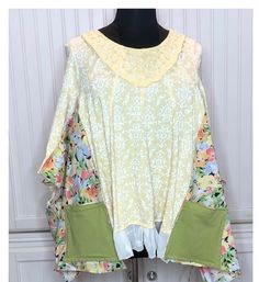 This easy fitting women's tee shirt tunic is made from a yellow and white print embroidered cotton tee, a floral print cotton, and some vintage lace.  The inspiration started with the embroidered yellow tee. I wanted to honor the beauty of this top, but upcycle it into an easy fitting piece. The yellow tee was used as the center base piece and the sides and sleeves were upsized using the floral print cotton, and the vintage lace was used to extend the hemline. The sides and hem flow gracefully. There are two large green cotton side pockets.  The dress is a comfortable fitting women's XXL free size that flares gently at the sides under the kimono sleeves.  I think the technique used make this a very slimming fit. See measurements below.  As always, I fell in love with the material of this s Flowy Cotton Tops With Lace Trim, Spring Lagenlook Blouse Relaxed Fit, Oversized Tunic Tops For Spring, Oversized Floral Print Top For Daywear, Oversized Spring Tunic Tops, Bohemian Cotton Tops One Size, Green Cotton Blouse With Patchwork, Green Cotton Patchwork Blouse, Oversized White Blouse With Floral Print