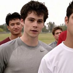 a group of young men standing next to each other in front of a green field