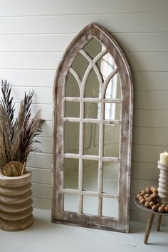 an old window is next to a potted plant and a candle on a table