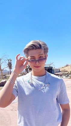 a young man wearing glasses standing in the desert