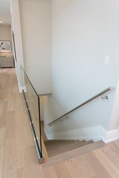 an empty room with a stair case and hard wood flooring on the bottom level