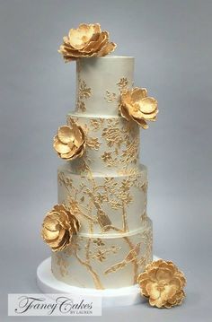 a three tiered cake with gold flowers on it's top and bottom layer