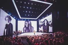 a large screen with two women on it in front of an audience