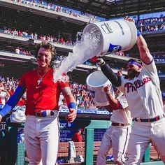 two baseball players are spraying water on each other with buckets in their hands while the crowd looks on