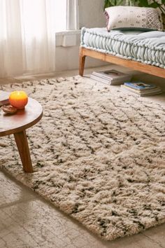 a living room with a couch, coffee table and rug on the floor in front of a window