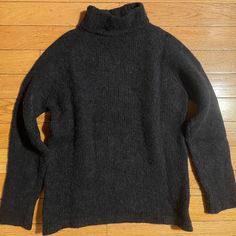 a black sweater sitting on top of a wooden floor