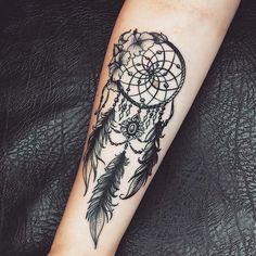 a woman's arm with a tattoo on it that has a dream catcher in the middle