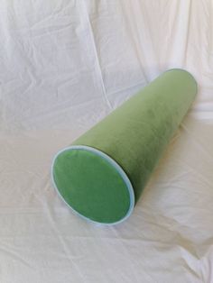 a green and white pillow on a white sheeted surface with the top rolled up