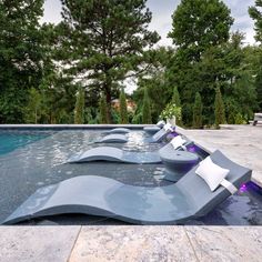 an outdoor swimming pool with lounge chairs and trees in the backgroung area