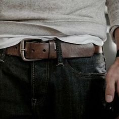 a man wearing a belt with his hands in his pockets