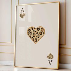 a leopard print heart on a white background in front of a gold framed art piece