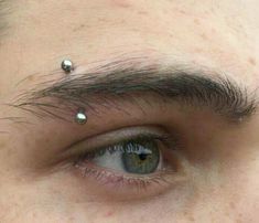 a man with piercings on his forehead looking at the camera