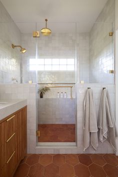 a bathroom with two towels hanging on the wall and one towel rack in the shower